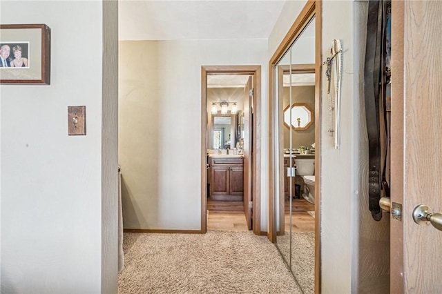 hall featuring baseboards and light colored carpet