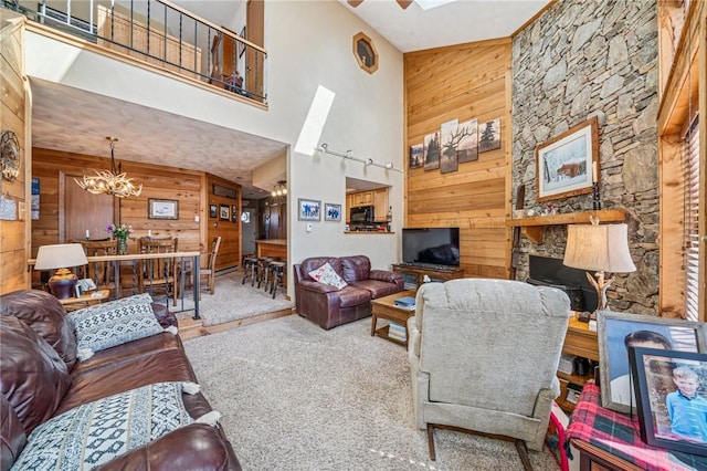 living area with a chandelier, a fireplace, wood walls, and a towering ceiling