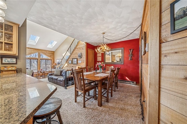 carpeted dining area with stairs, lofted ceiling with skylight, baseboard heating, and a notable chandelier