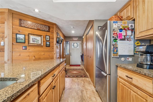 kitchen with recessed lighting, light stone counters, and freestanding refrigerator