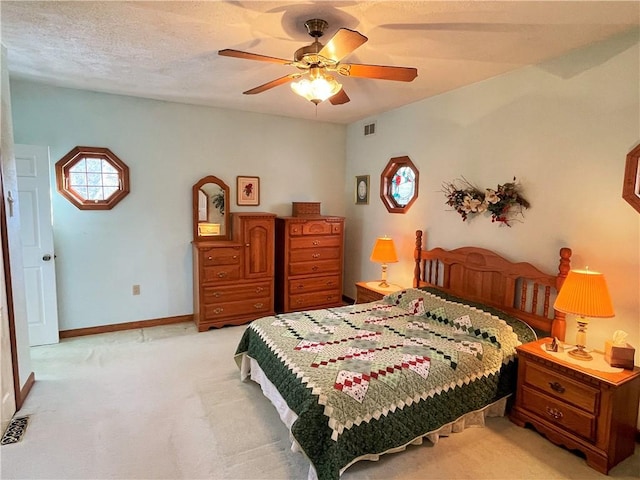 bedroom featuring ceiling fan, a textured ceiling, light carpet, visible vents, and baseboards