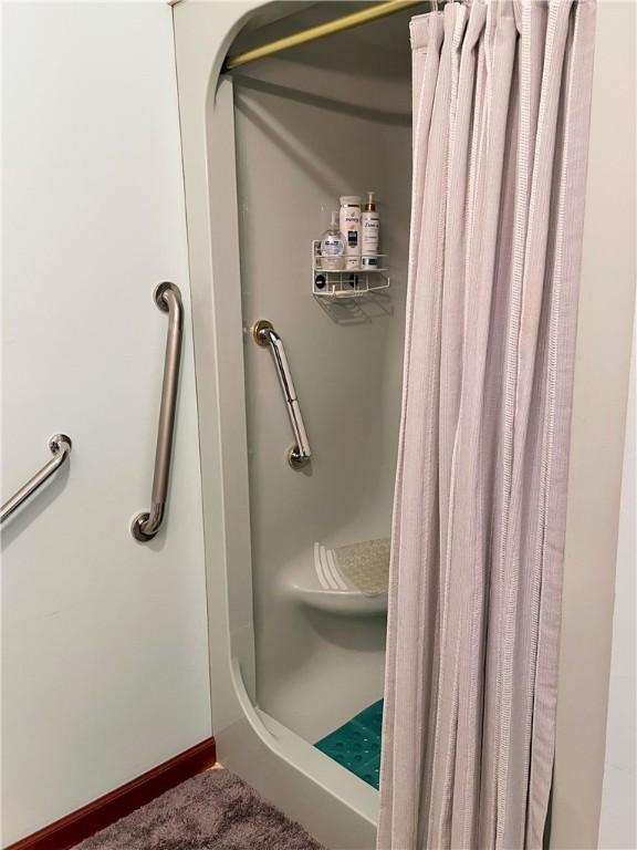 bathroom featuring a shower stall and baseboards