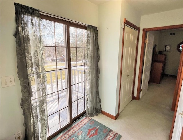 doorway featuring baseboards and light colored carpet