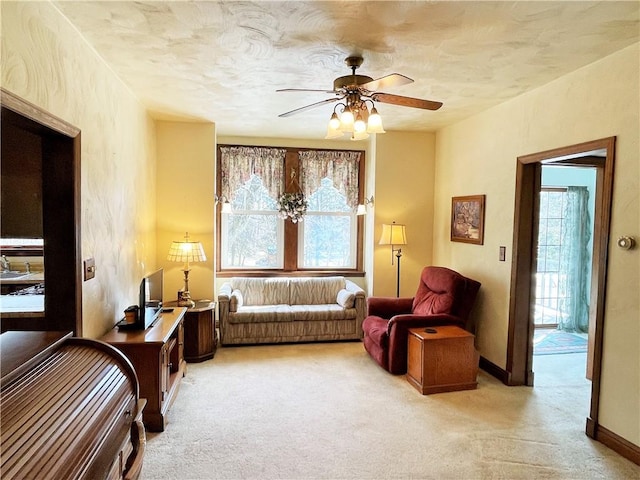 sitting room featuring ceiling fan, baseboards, a textured ceiling, and light colored carpet