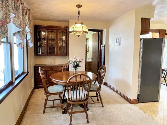 dining space featuring light carpet and baseboards