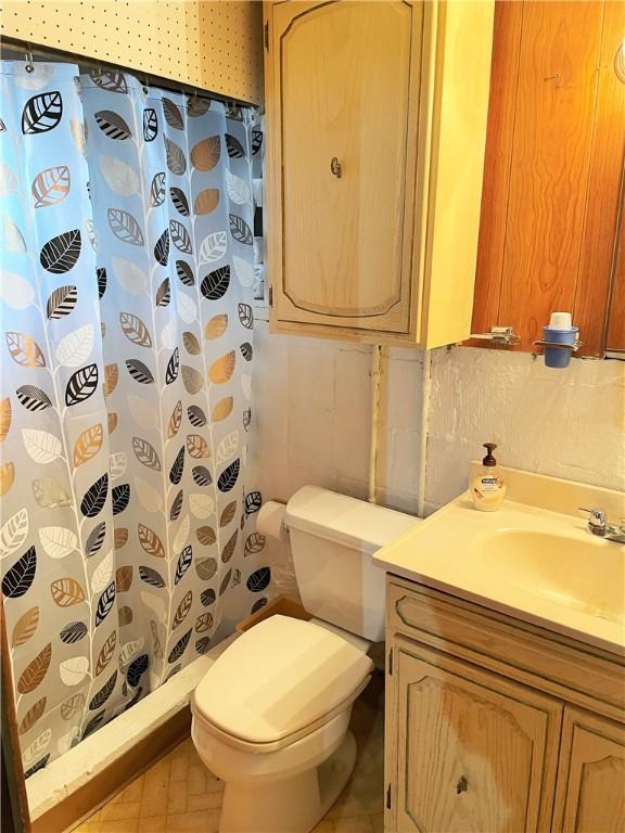 bathroom with toilet, curtained shower, tile patterned flooring, and vanity