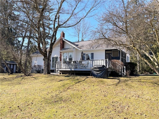 view of front of home with a deck, a chimney, and a front lawn