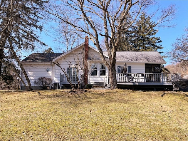 back of property with a chimney, a deck, and a yard