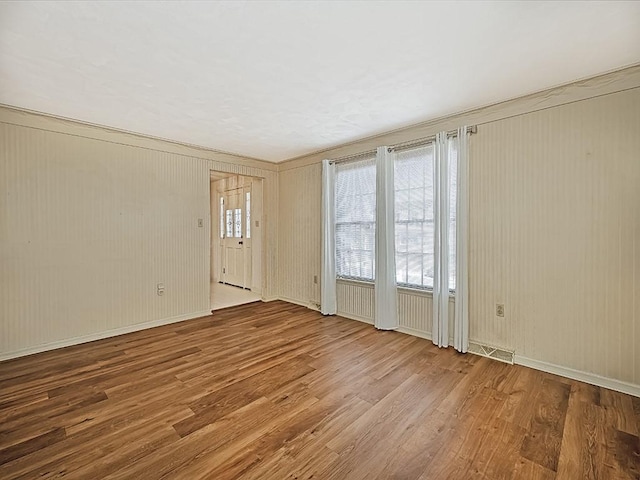 spare room featuring visible vents, baseboards, and wood finished floors