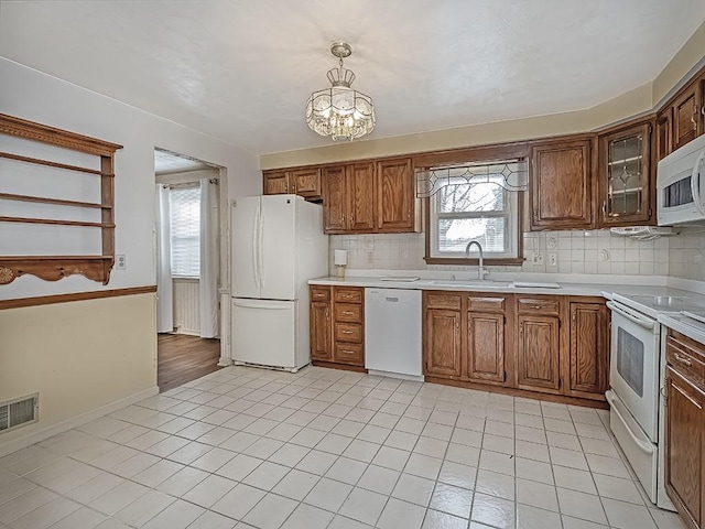 kitchen with light countertops, white appliances, a sink, and a healthy amount of sunlight