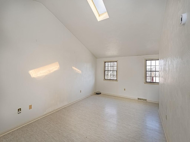 unfurnished room with vaulted ceiling with skylight and visible vents