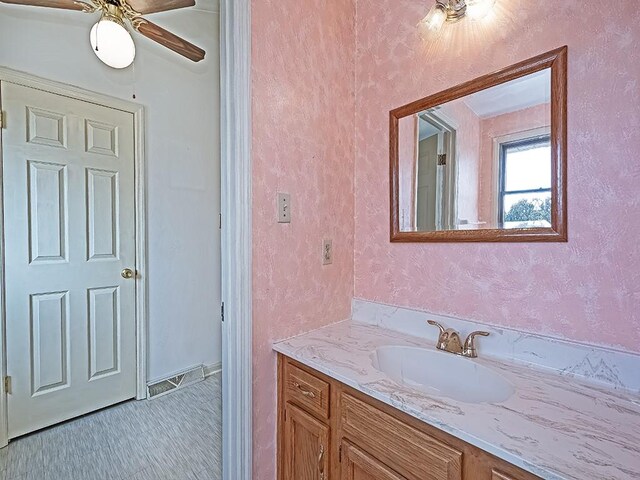 bathroom featuring a textured wall, a ceiling fan, and vanity