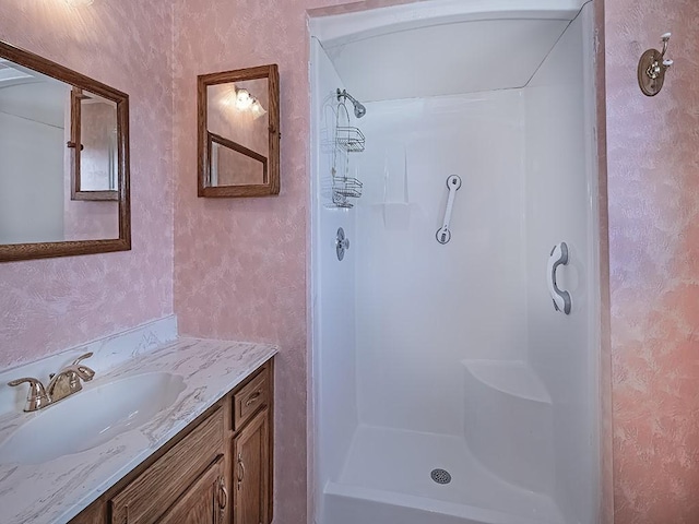 full bathroom featuring wallpapered walls, vanity, walk in shower, and a textured wall