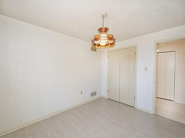 unfurnished bedroom with baseboards, visible vents, light wood-style flooring, and a closet