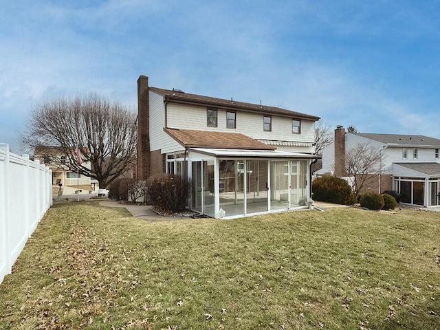 back of house with a sunroom, a fenced backyard, a yard, and a chimney