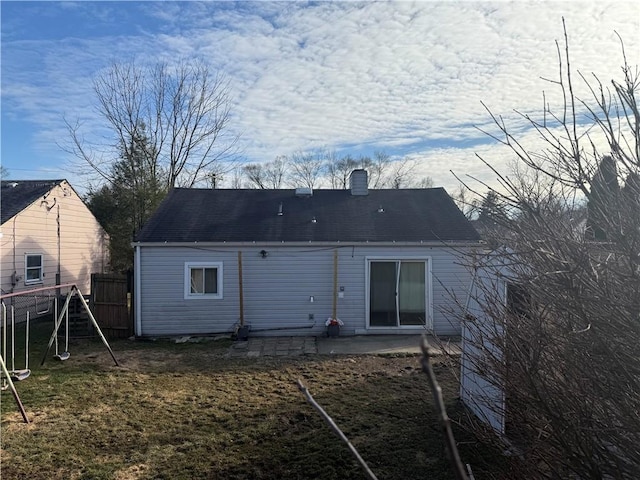 rear view of house with a patio, a chimney, a playground, and fence