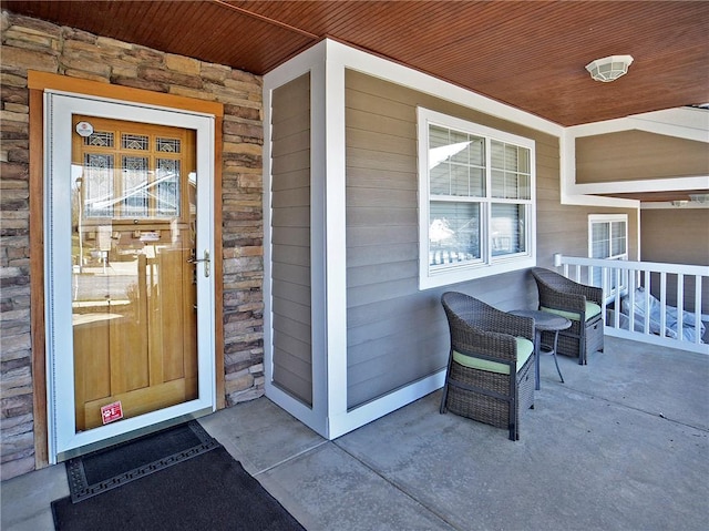 doorway to property with a porch and stone siding