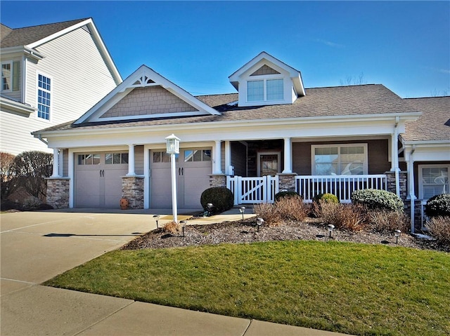 craftsman house with a garage, covered porch, a front lawn, and concrete driveway