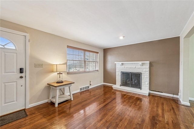 entrance foyer with baseboards, a fireplace, visible vents, and wood finished floors