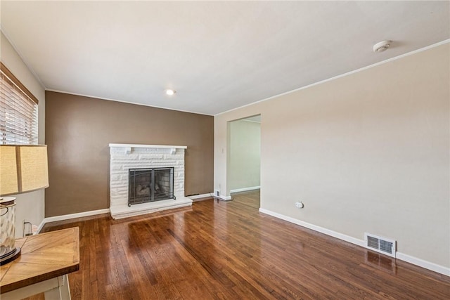 unfurnished living room featuring baseboards, a fireplace, visible vents, and wood finished floors