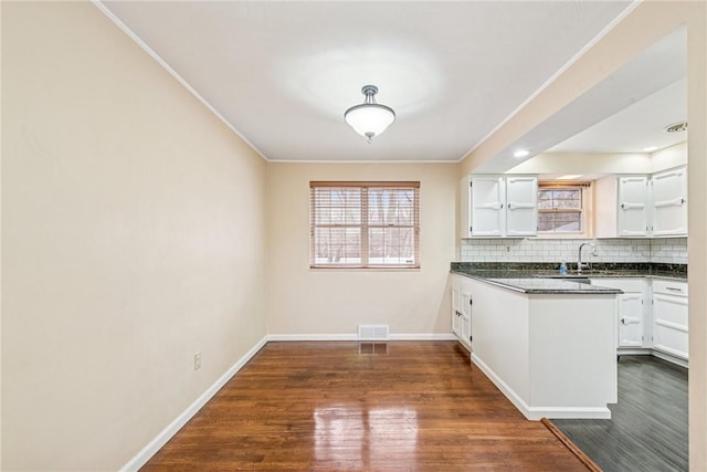 kitchen featuring dark countertops, white cabinets, decorative backsplash, and dark wood finished floors