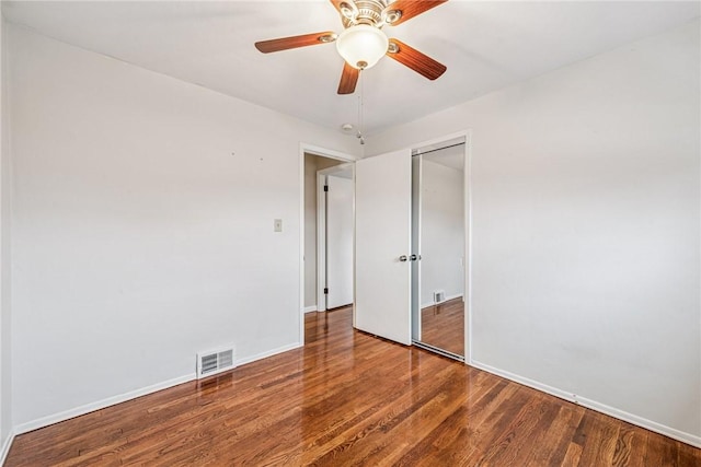 unfurnished bedroom featuring ceiling fan, wood finished floors, visible vents, baseboards, and a closet