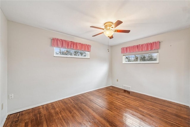 empty room with ceiling fan, wood finished floors, visible vents, and baseboards