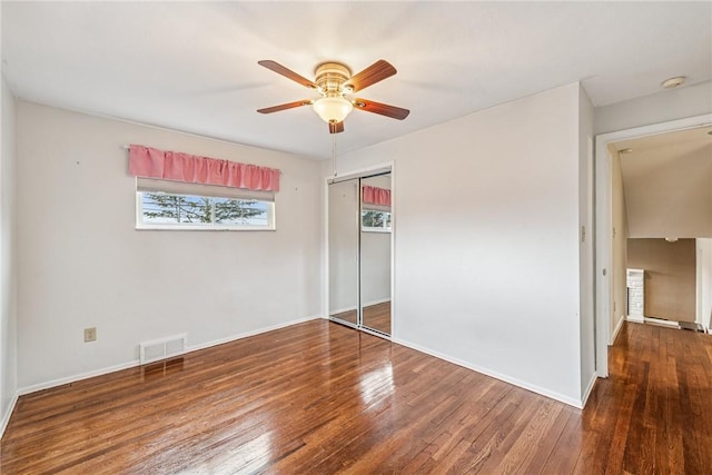 unfurnished bedroom featuring baseboards, a closet, visible vents, and hardwood / wood-style floors