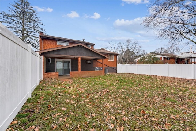 back of property featuring brick siding, a yard, and a fenced backyard