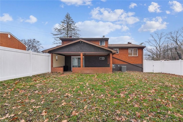 exterior space featuring a fenced backyard, a front lawn, central AC, and brick siding