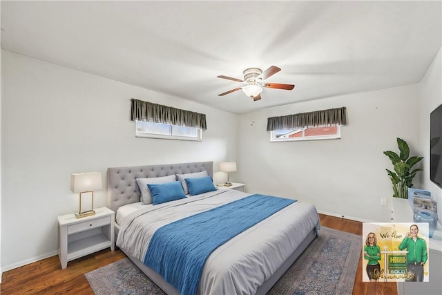 bedroom with multiple windows, wood finished floors, and baseboards