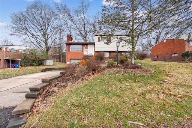 view of front of house featuring an attached garage, brick siding, concrete driveway, a front lawn, and a chimney