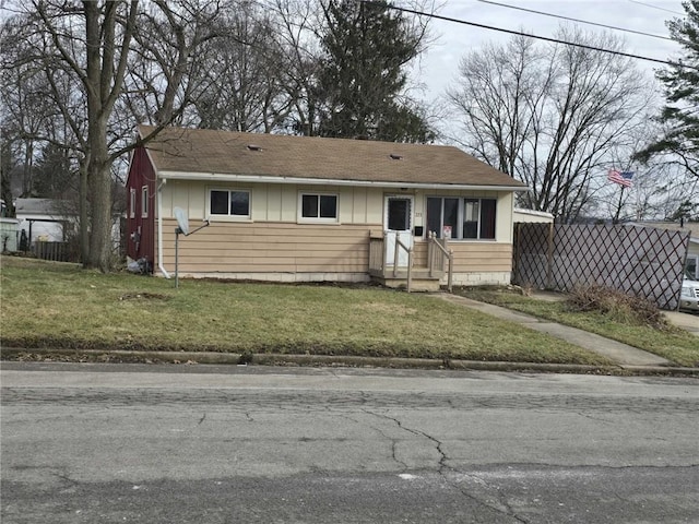 view of front of home featuring a shingled roof, fence, and a front yard