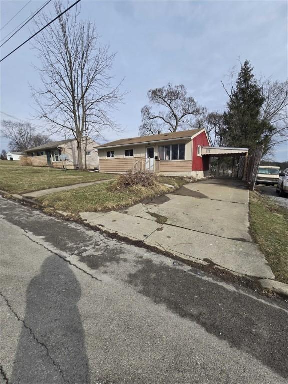 view of front of house with concrete driveway, an attached carport, and a front lawn