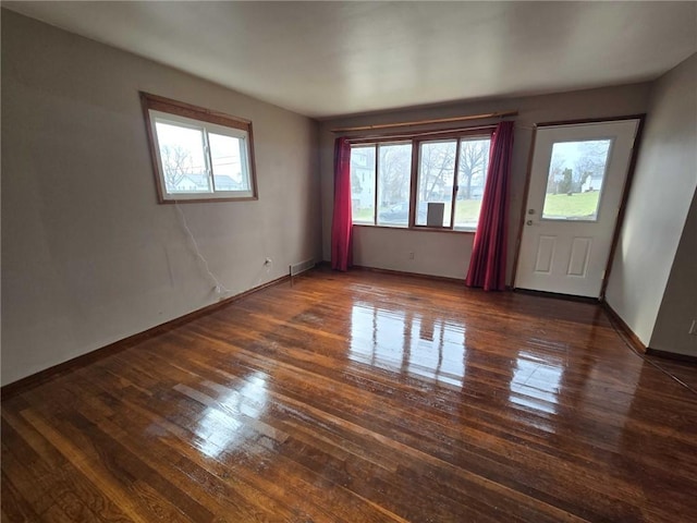 unfurnished room featuring baseboards, a healthy amount of sunlight, and hardwood / wood-style floors