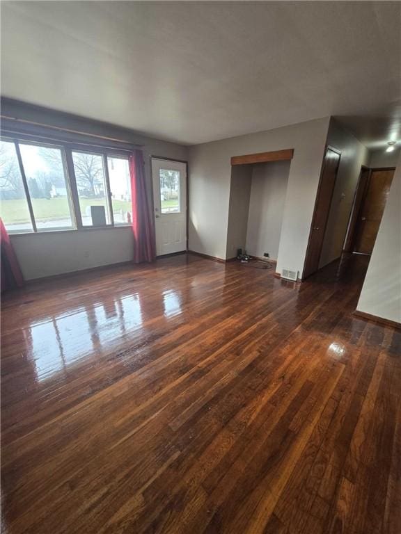 unfurnished room featuring visible vents, dark wood finished floors, and baseboards