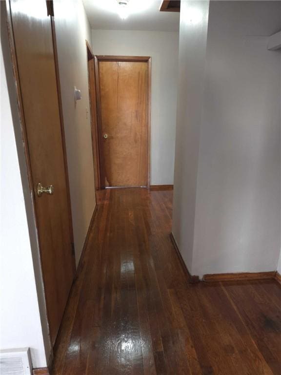 hall featuring wood-type flooring, visible vents, and baseboards