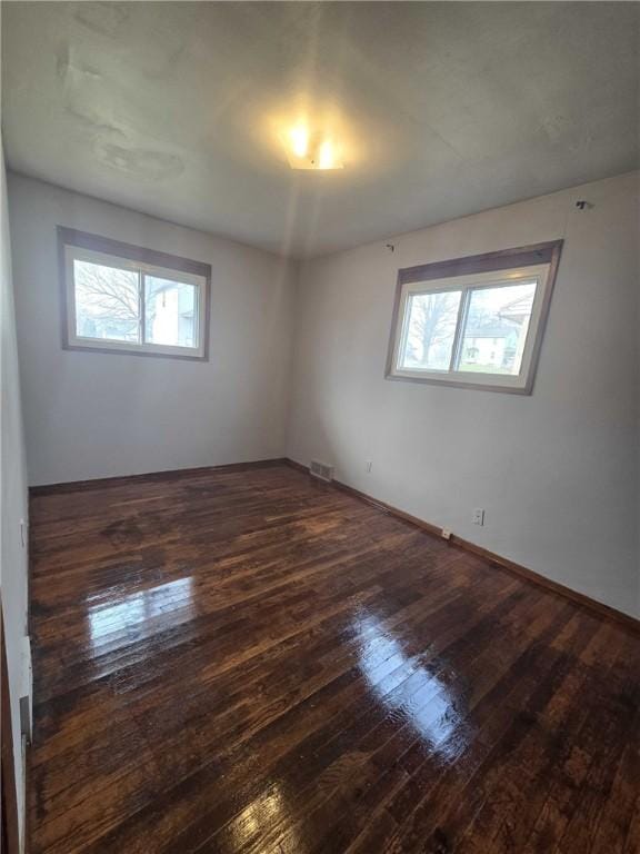 empty room featuring visible vents, plenty of natural light, and hardwood / wood-style flooring