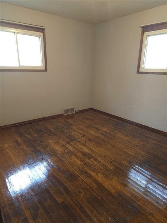 unfurnished room with wood-type flooring and visible vents