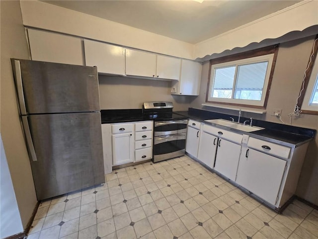 kitchen with a sink, white cabinetry, appliances with stainless steel finishes, light floors, and dark countertops