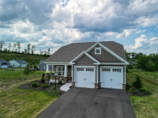 view of front of home featuring board and batten siding, stone siding, driveway, and a shingled roof