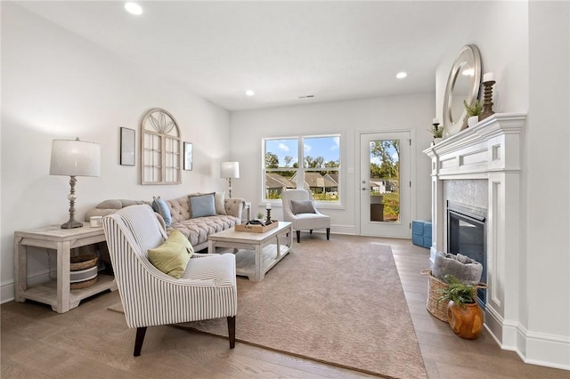 living area featuring baseboards, light wood finished floors, a fireplace, and recessed lighting