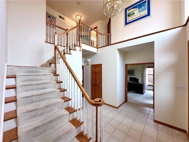 stairs with tile patterned flooring, a towering ceiling, visible vents, and baseboards