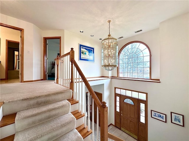 foyer entrance with a chandelier, stairway, visible vents, and baseboards