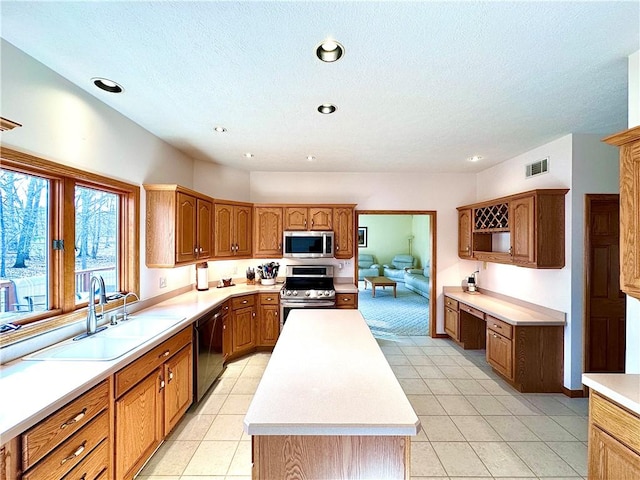 kitchen featuring a center island, light countertops, visible vents, appliances with stainless steel finishes, and a sink