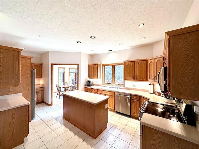 kitchen featuring a center island, brown cabinets, light countertops, appliances with stainless steel finishes, and a sink