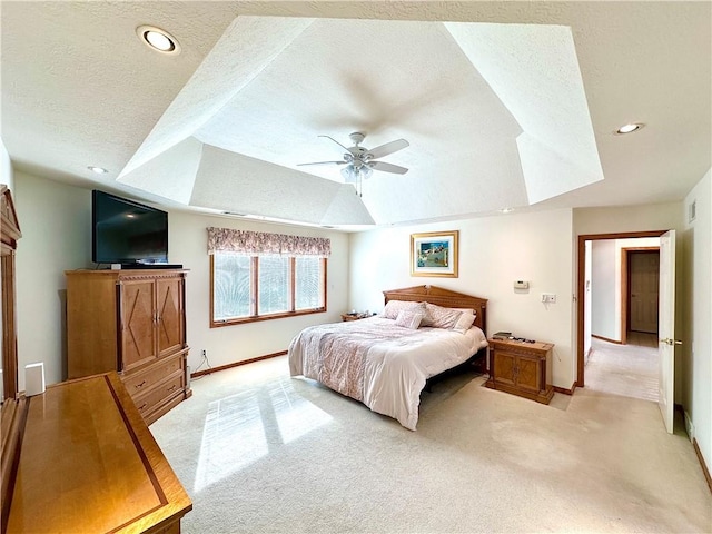 bedroom with a textured ceiling, recessed lighting, a raised ceiling, and light colored carpet