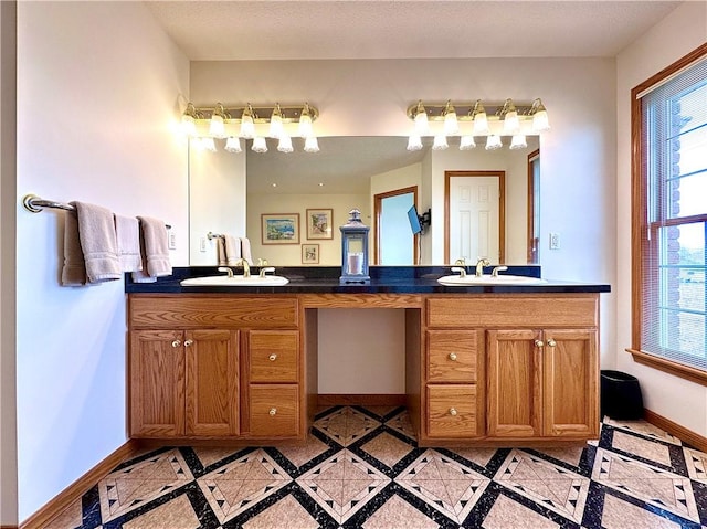 bathroom with double vanity, baseboards, and a sink