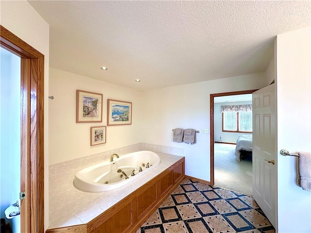 ensuite bathroom with recessed lighting, connected bathroom, a textured ceiling, baseboards, and a tub with jets