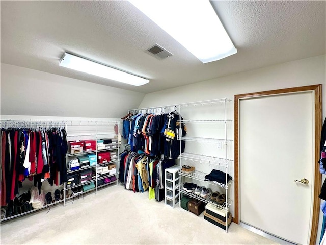 spacious closet with lofted ceiling, visible vents, and carpet flooring